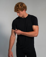 Man wearing a black t-shirt against a gray background
