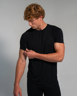 Man wearing a black t-shirt against a gray background